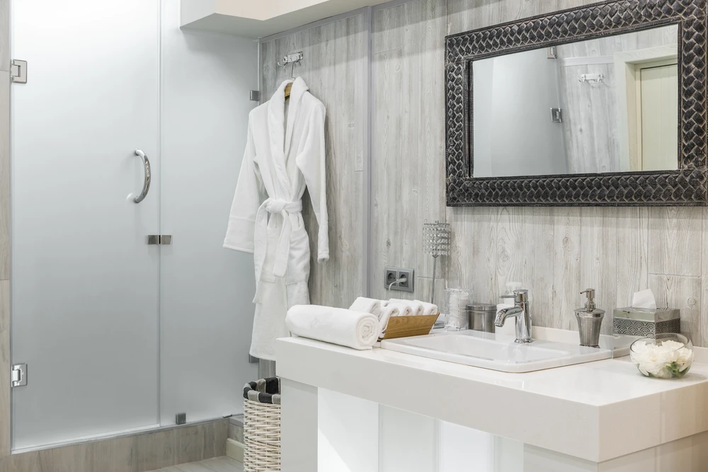 Salle de bain moderne haut de gamme avec douche à l'italienne vitrée, vasque rectangulaire blanche sur plan de toilette, robinetterie chromée contemporaine